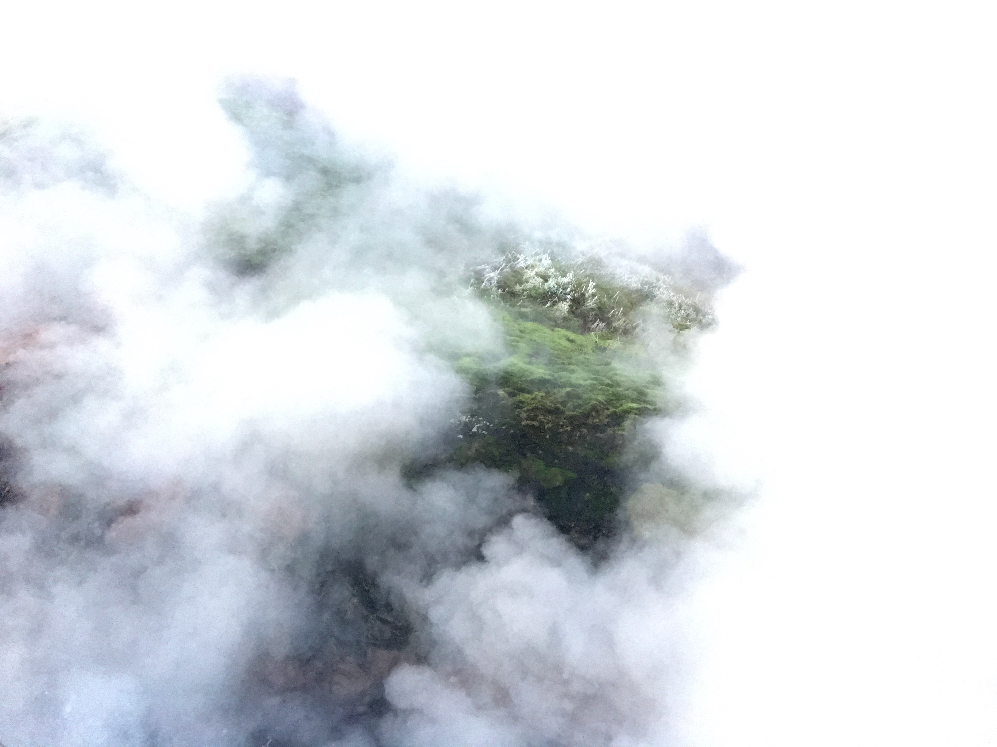 Green landscape surrounded by mist of hot springs